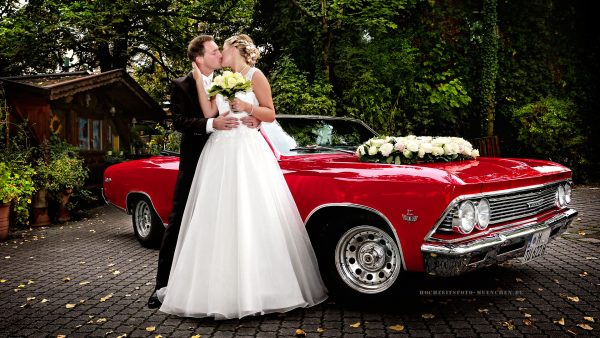 Brautpaar mit rotem Hochzeitsauto